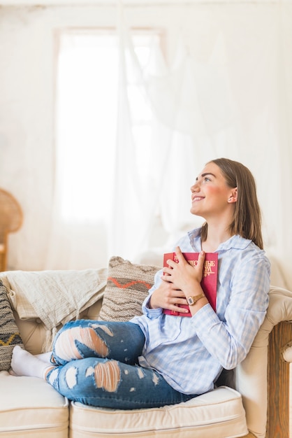 Giovane donna sorridente che tiene libro rosso