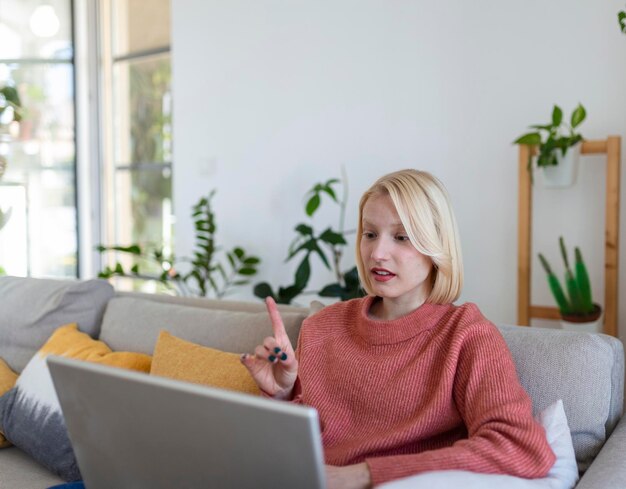 Giovane donna sorridente che utilizza il laptop a casa guardando lo schermo in chat indossando cuffie wireless con tutor aziendale in videoconferenza tramite webcam concetto di ecoaching di formazione online