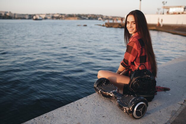 giovane donna sorridente con scooter elettrico all'aperto