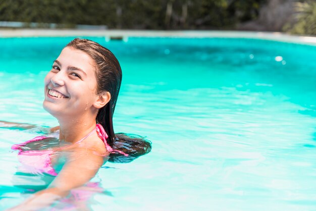 Giovane donna sorridente in bikini in piscina