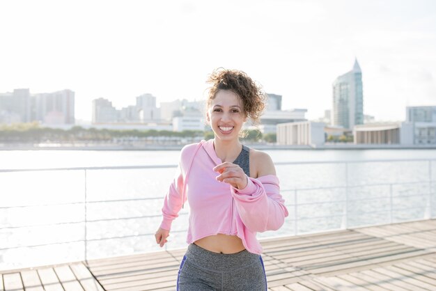 Giovane donna sportiva allegra che fa jogging sulla banchina