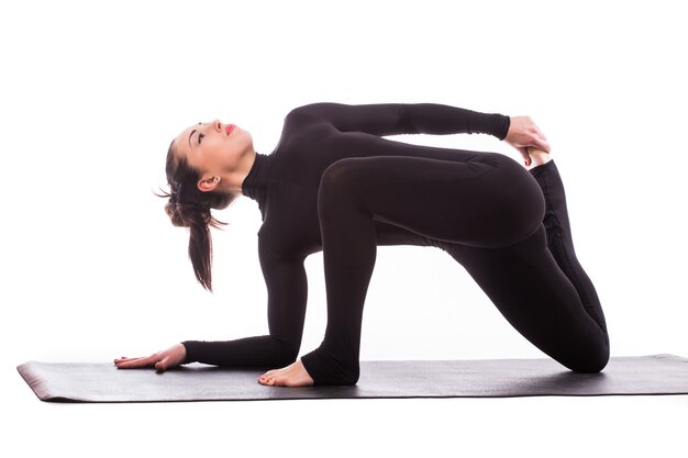 Giovane donna sportiva che fa pratica yoga isolata su priorità bassa bianca - il concetto di vita sana e l'equilibrio naturale tra il corpo e lo sviluppo mentale