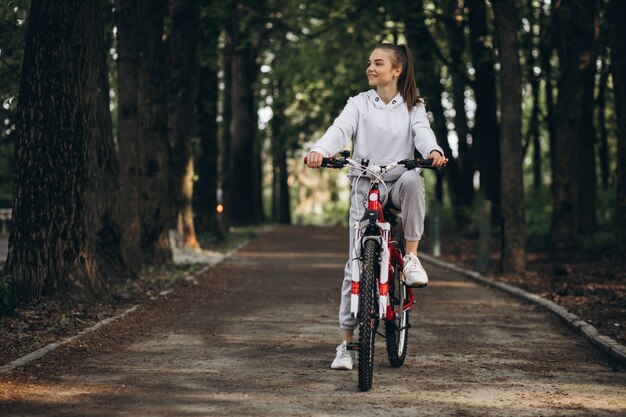 Giovane donna sportiva che guida la bicicletta nel parco