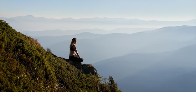 Giovane donna sportiva che medita nelle montagne