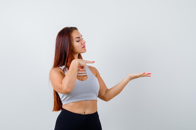 Giovane donna sportiva con i capelli lunghi in un top grigio