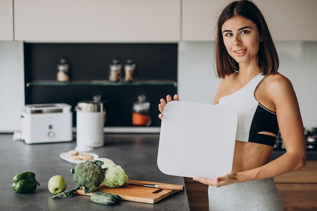 Giovane donna sportiva con scale in cucina