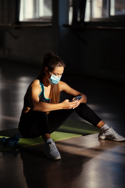 Giovane donna sportiva dopo la pratica dello yoga, pausa nel fare esercizio, rilassarsi sul materassino yoga