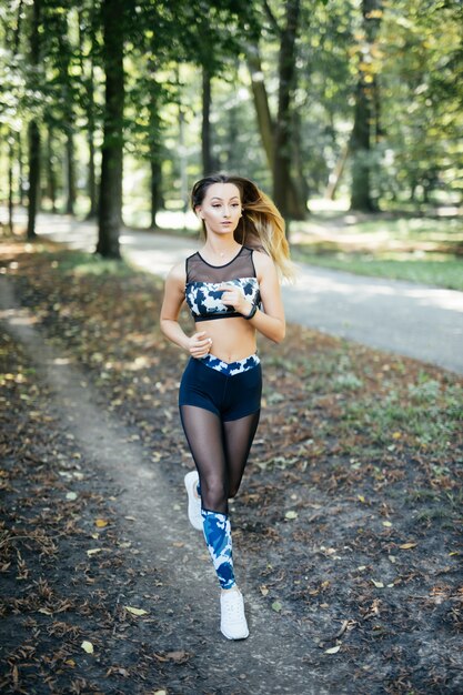 Giovane donna sportiva sorridente che corre all'aperto nel parco