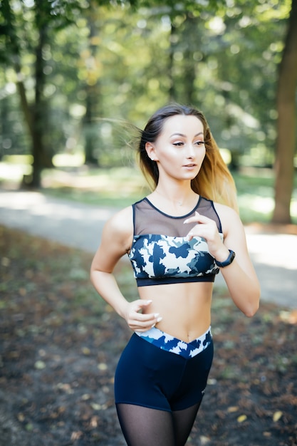 Giovane donna sportiva sorridente che corre all'aperto nel parco