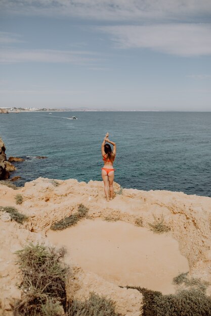 Giovane donna su una spiaggia su un bellissimo mare braccia in aria sulla spiaggia