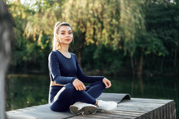 Giovane donna su una stuoia di yoga che si rilassa all'aperto