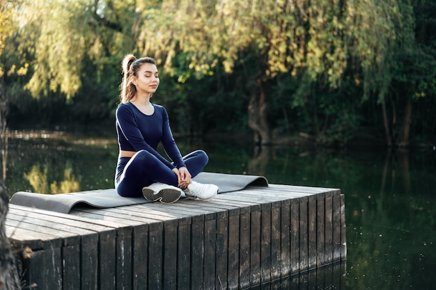 Giovane donna su una stuoia di yoga che si rilassa all'aperto