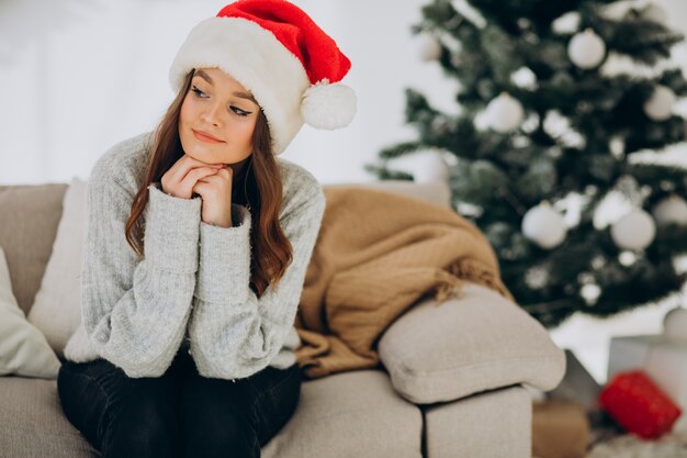 Giovane donna sul divano vicino all'albero di Natale