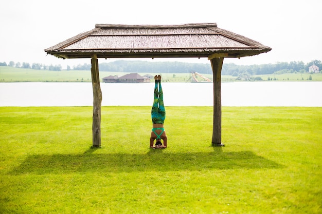 Giovane donna sveglia che fa esercizi di handstand nel parco verde