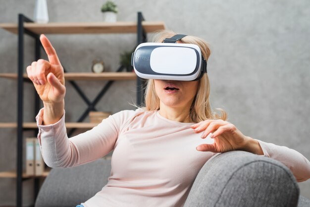 Giovane donna utilizzando una cuffia di realtà virtuale che punta il dito contro qualcosa