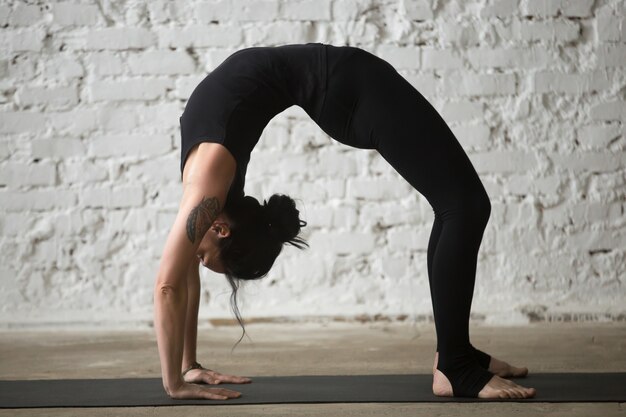 Giovane donna yogi attraente in Urdhva Dhanurasana posa, loft bac