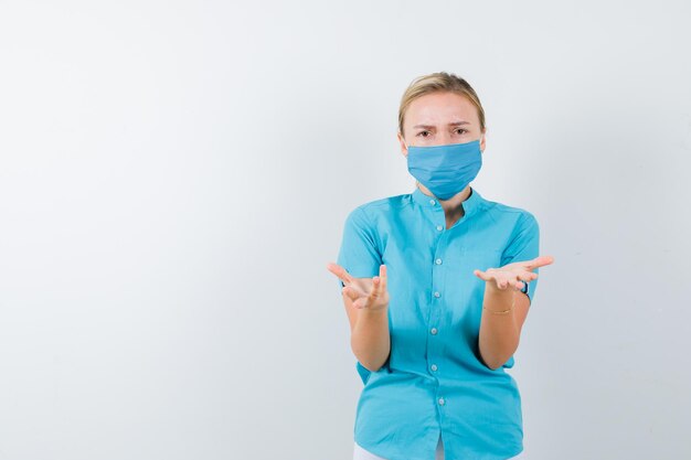 Giovane dottoressa che finge di mostrare qualcosa in uniforme isolata