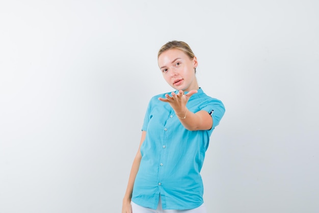 Giovane dottoressa che mostra un gesto in uniforme medica, maschera e sembra carina looking