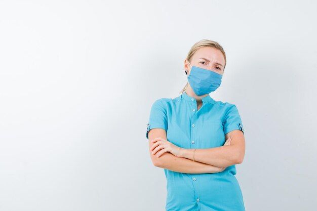 Giovane dottoressa in uniforme in piedi con le braccia incrociate isolate