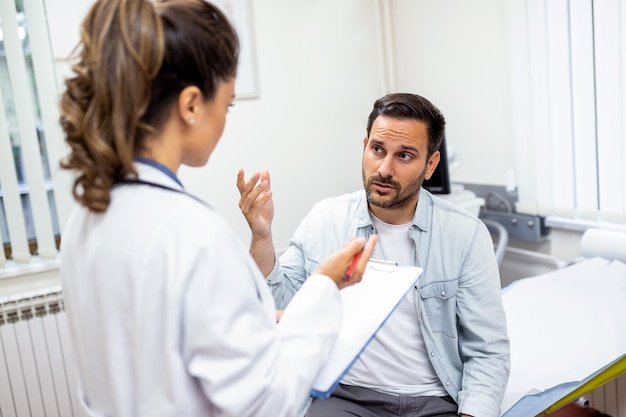 Giovane dottoressa professionista medico che consulta il paziente che parla con il cliente adulto dell'uomo alla visita di controllo medico concetto di assistenza sanitaria per il trattamento delle malattie