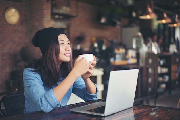 Giovane e bella donna pantaloni a vita bassa che si siede in un caffè, tenendo