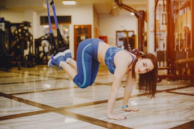 giovane e bella ragazza in una tuta sportiva blu è impegnata nello sport in palestra