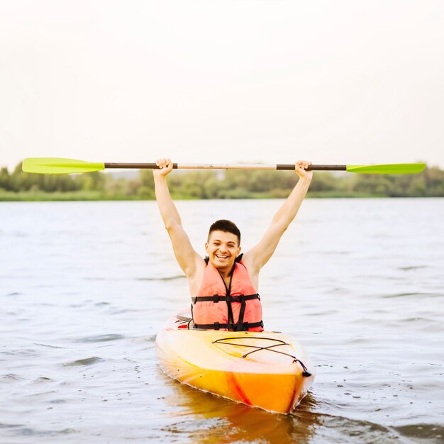 Giovane emozionante che tiene remo nella sua mano che kayaking sopra come