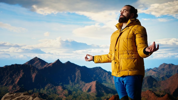 Foto gratuito giovane esploratore che raggiunge la vetta della montagna e medita in cima
