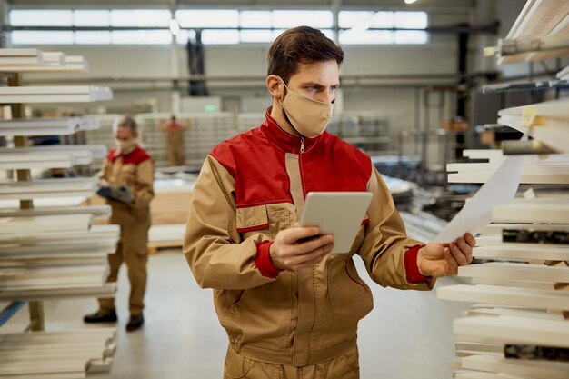 Giovane falegname che utilizza una tavoletta digitale mentre esamina la lista di controllo in un'officina