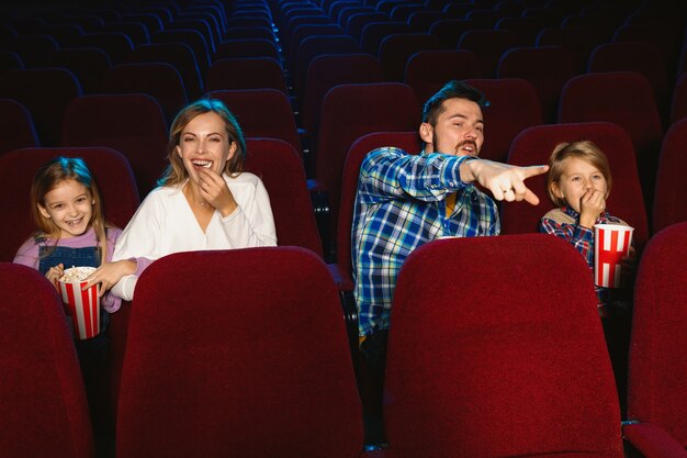 Giovane famiglia caucasica guardando un film in un cinema, casa o cinema. Guarda espressivo, stupito ed emotivo. Seduto da solo e divertendomi. Relazione, amore, famiglia, infanzia, fine settimana.