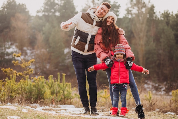 Giovane famiglia che cammina insieme nella foresta all'orario invernale