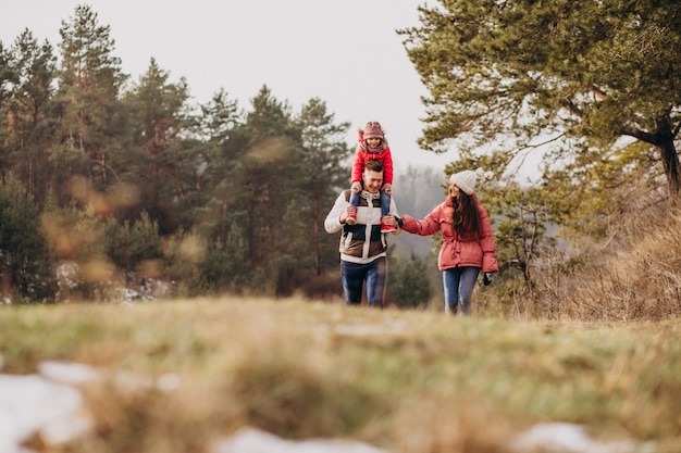 Giovane famiglia che cammina insieme nella foresta all'orario invernale