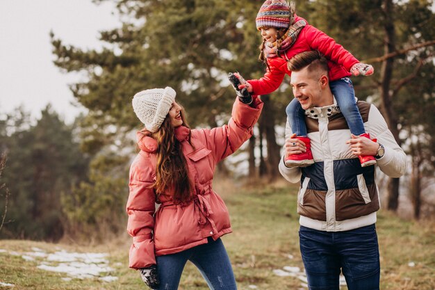 Giovane famiglia che cammina insieme nella foresta all'orario invernale