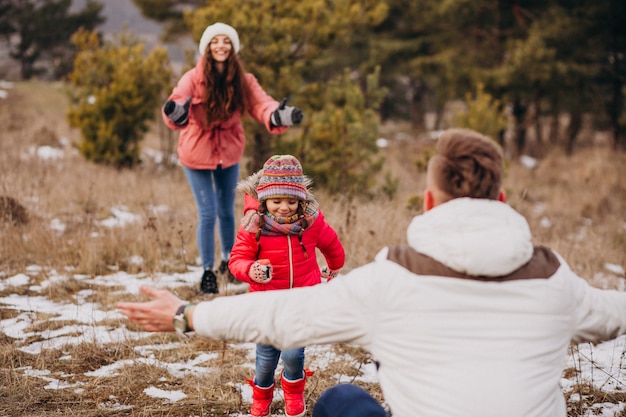 Giovane famiglia che cammina insieme nella foresta all'orario invernale