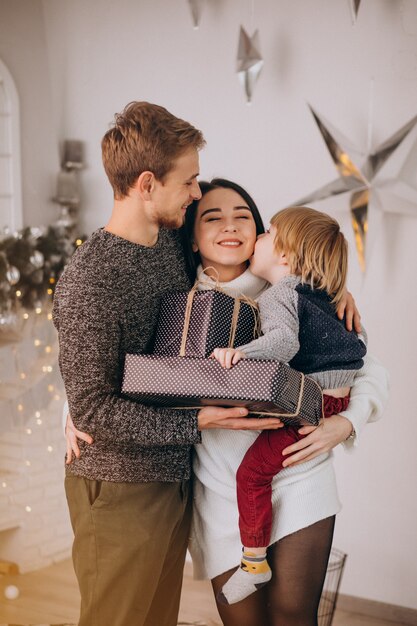 Giovane famiglia che disimballa i regali con il piccolo figlio su Natale