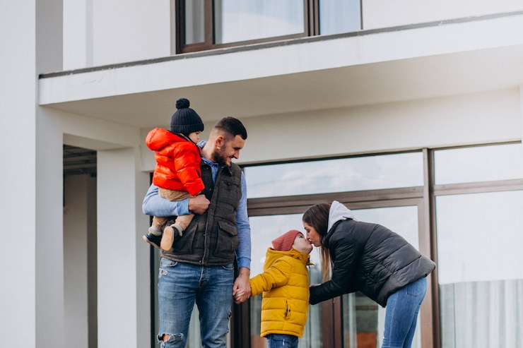 Foto gratuito giovane famiglia con due fratellini vicino alla casa