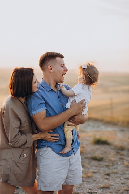 Giovane famiglia con figlia del bambino sul tramonto in un campo