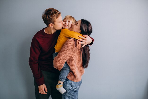 Giovane famiglia con figlio piccolo insieme su grigio