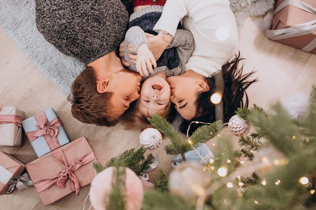 Giovane famiglia con figlio piccolo sotto l'albero di Natale