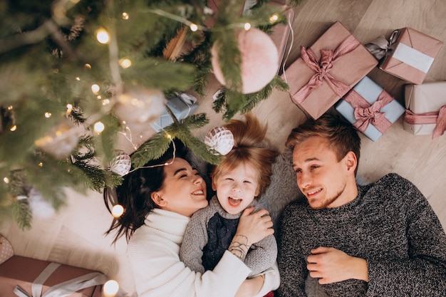 Giovane famiglia con figlio piccolo sotto l'albero di Natale