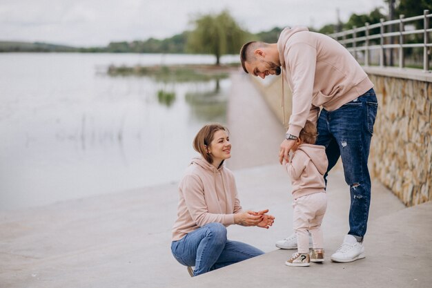 Giovane famiglia con il loro piccolo bambino nel parco in riva al lago