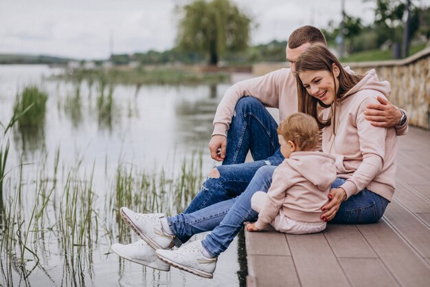 Giovane famiglia con il loro piccolo bambino nel parco in riva al lago