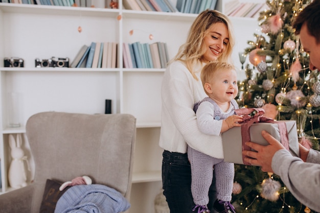 Giovane famiglia con la piccola figlia che tiene i regali di Natale