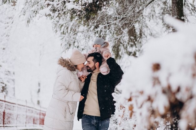 Giovane famiglia con la piccola figlia in una foresta di inverno piena di neve