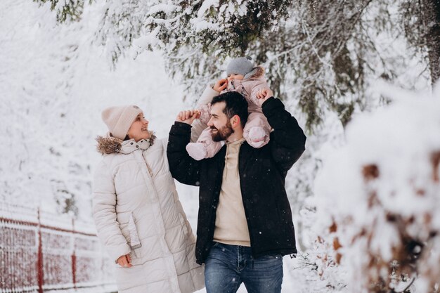 Giovane famiglia con la piccola figlia in una foresta di inverno piena di neve