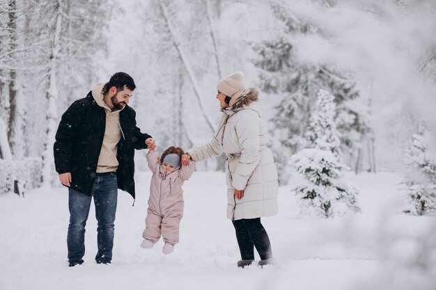 Giovane famiglia con la piccola figlia in una foresta di inverno piena di neve