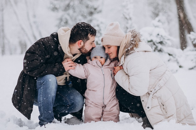 Giovane famiglia con la piccola figlia in una foresta di inverno piena di neve