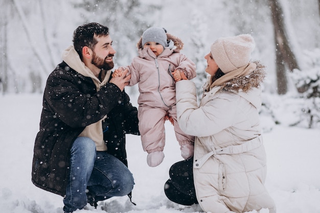 Giovane famiglia con la piccola figlia in una foresta di inverno piena di neve