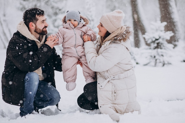 Giovane famiglia con la piccola figlia in una foresta di inverno piena di neve