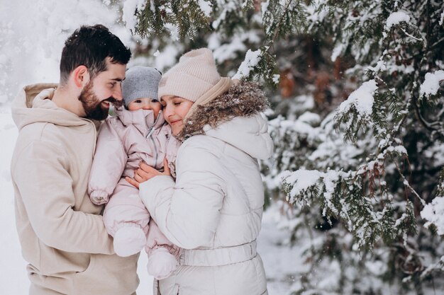 Giovane famiglia con la piccola figlia in una foresta di inverno piena di neve